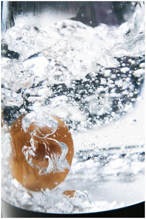 A detailed shot capturing an egg boiling in a pot,