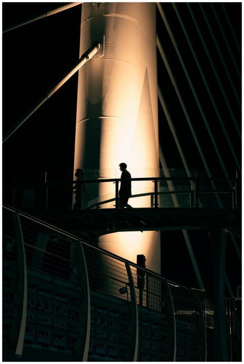 A silhouette of a person walking on a lit-up moder