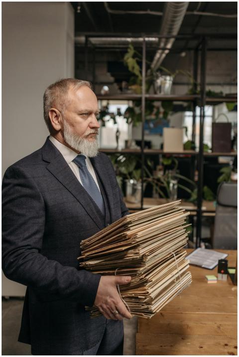 Elderly businessman in a suit holding a large pile