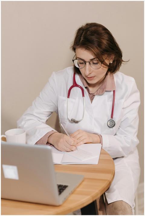 Female doctor with stethoscope writing notes in an