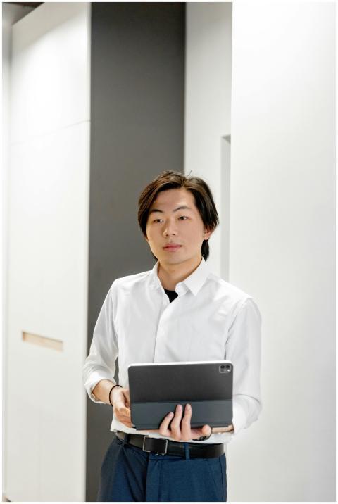 Confident man in white shirt with tablet, stands i