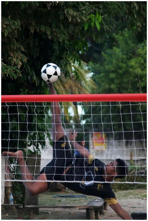 Athletic futevôlei player performing a high kick o