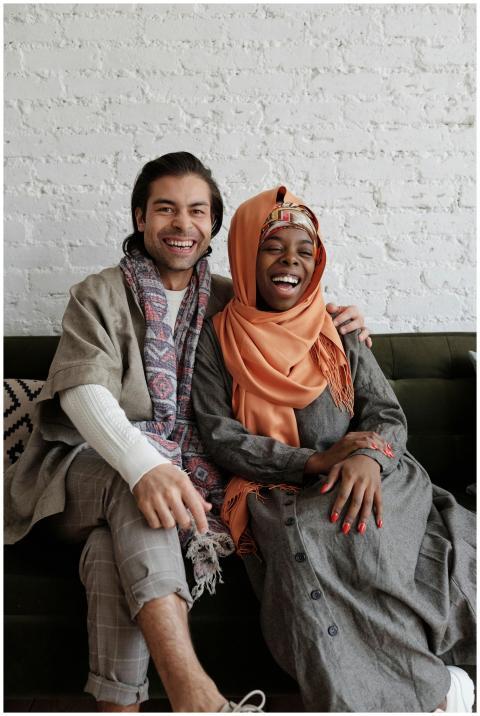Smiling multiethnic couple seated on a couch, shar