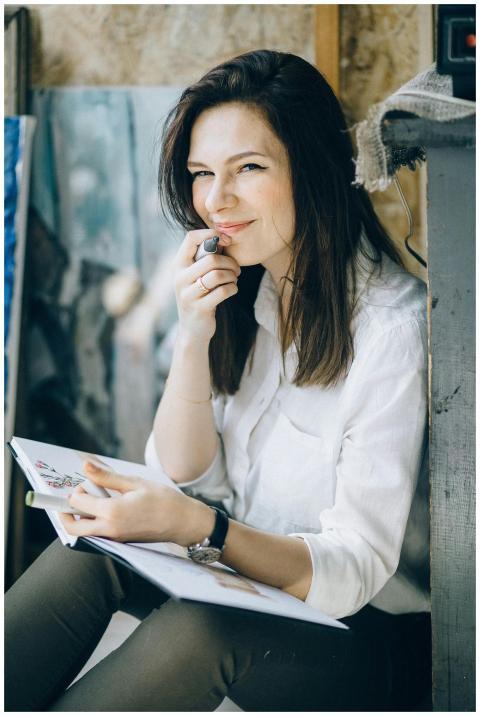 A woman in a white blouse smiles while holding a b