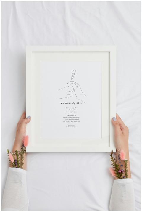 Hands holding a framed inspirational quote on a wh