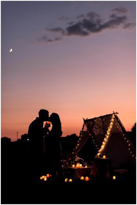 Silhouetted couple embracing by candlelit picnic s