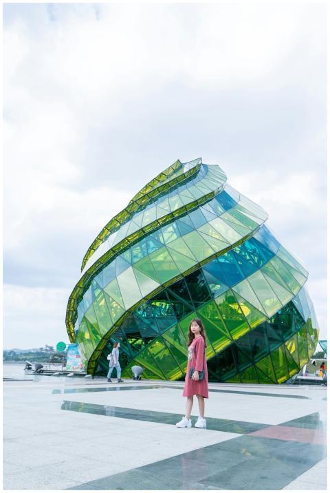 A young Asian woman poses in front of the iconic g