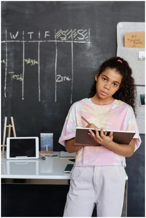 A child stands at a desk with a notebook in front