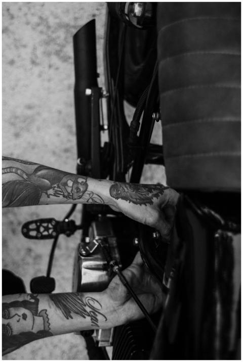 Black and white image of a man adjusting motorcycl