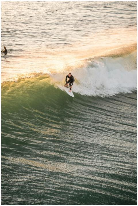 A surfer expertly rides a wave during sunset, show