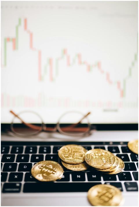 Bitcoin coins on a laptop with a financial chart,