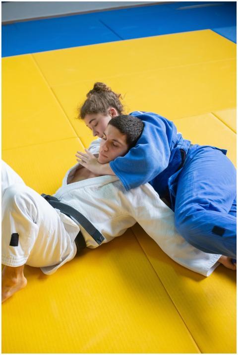Two adults practicing judo in a grappling hold on