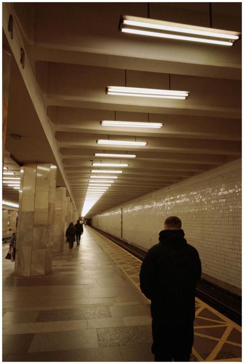 A moody subway platform with individuals waiting u