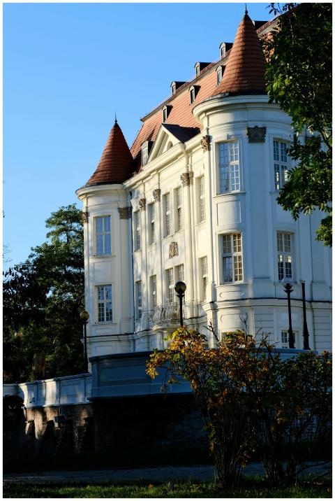 A beautiful white historic mansion with red roof t