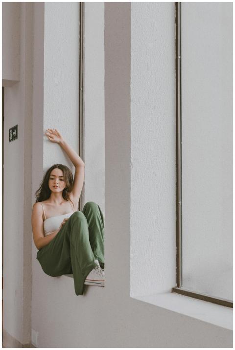 Young woman in green pants and white top sitting o