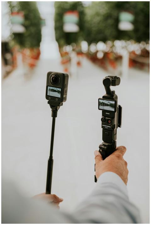 Hands holding advanced cameras capturing an outdoo