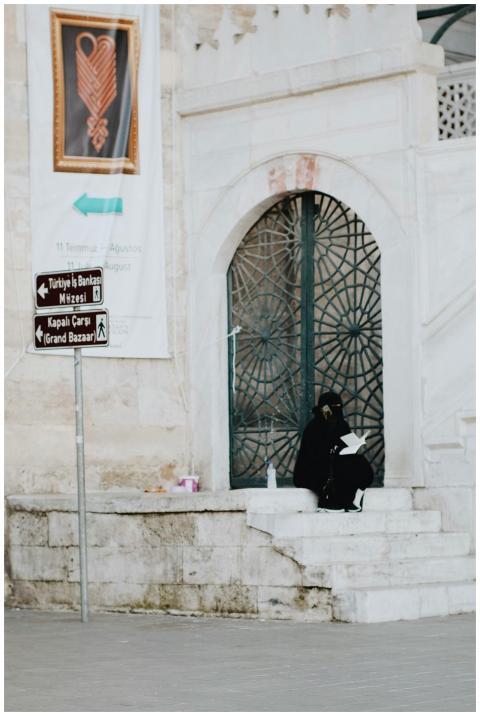 A woman in traditional attire sits near a historic