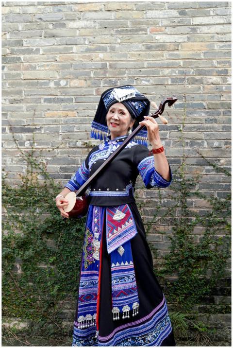 Woman in traditional Zhuang attire playing a strin