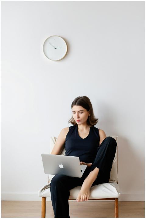 A woman sitting on a chair, using a laptop for rem