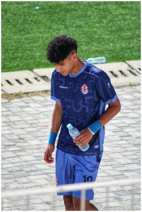 Teen soccer player walking on sports field holding