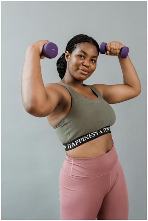 Confident woman in workout gear lifting dumbbells