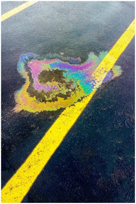 Vibrant rainbow-colored oil spill on black asphalt