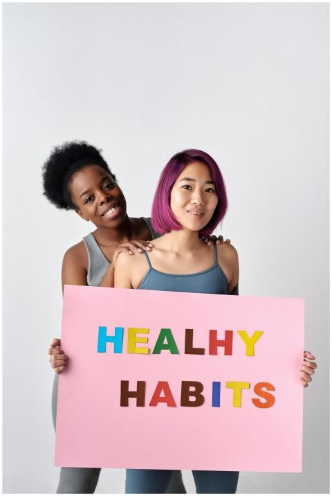 Two diverse women holding a healthy habits sign, p