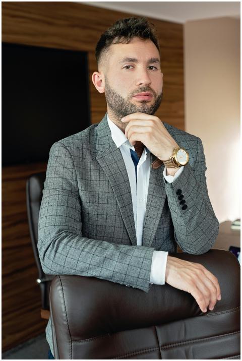 Confident man in gray suit posing in an office, co