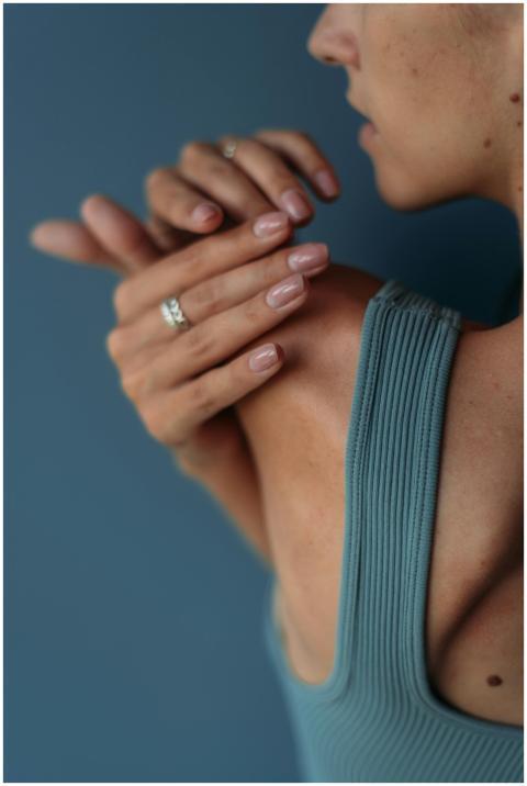 Close-up of a woman stretching her arm against a b