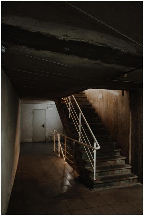 Explore a dimly lit abandoned stairwell with a spo