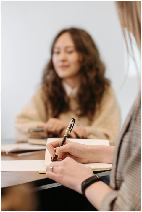 Close-up of hands writing in a notepad during a te