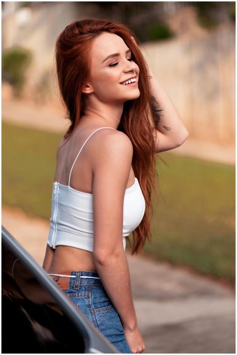 Young woman with long red hair smiling outdoors in