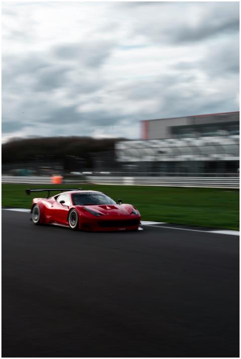 A red racing car speeds along a track, capturing t