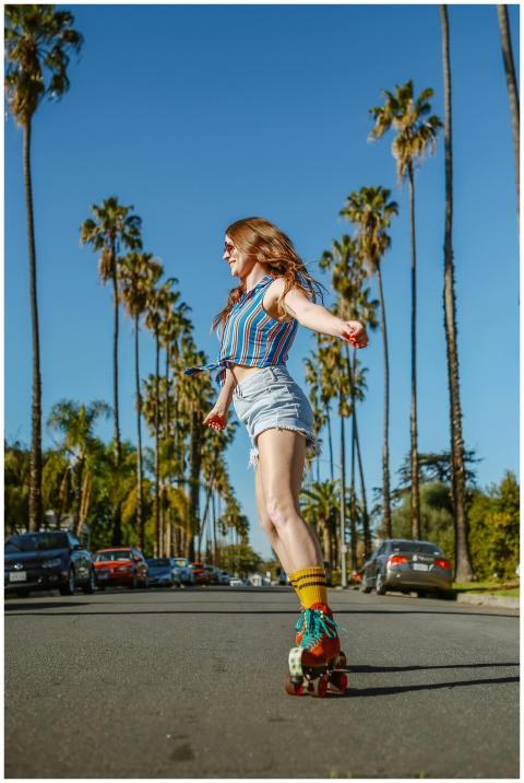 A carefree woman roller skating on a palm-lined st