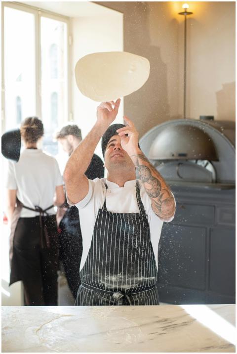 A chef in a traditional Portuguese bakery tosses p
