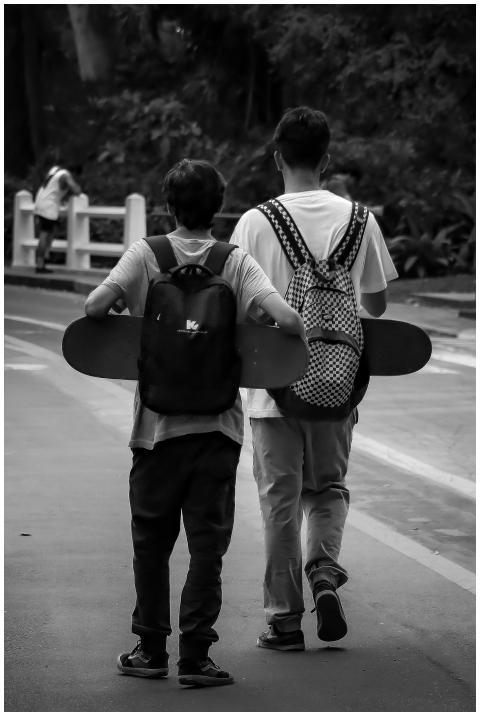 Two young men carrying skateboards stroll along a