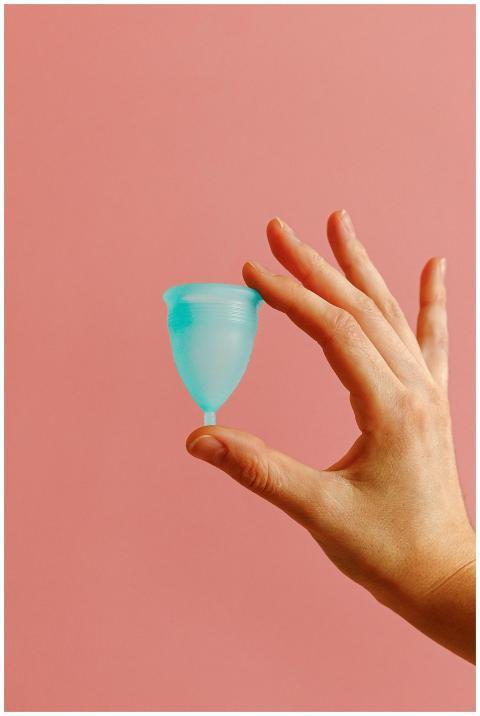 A reusable menstrual cup in a hand against a soft