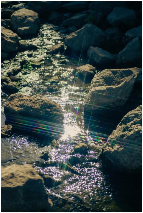 Capture of sunlit stream flowing over rocks in Укр