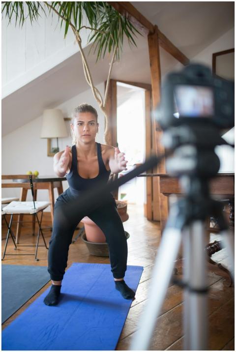 Young woman performing squats indoors in front of