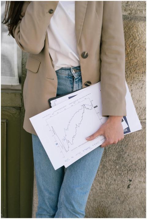 A person in casual business attire holding financi