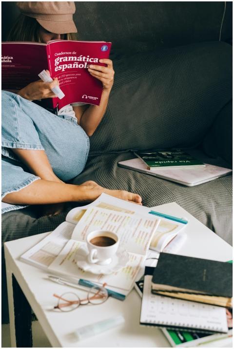 Woman studying Spanish grammar at home with coffee