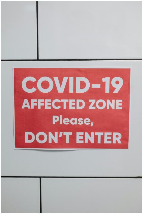Red sign warning of COVID-19 affected zone, advisi
