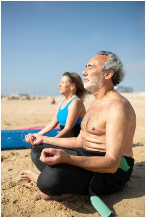 Elderly couple practicing yoga meditation on a ser