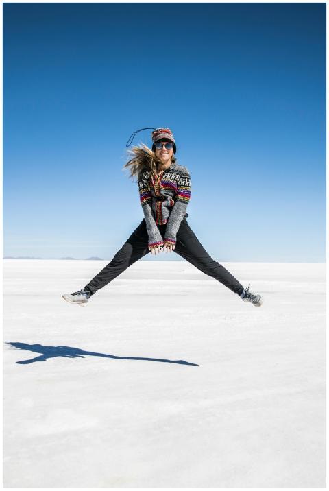 Woman jumping joyfully on the vast white expanse o