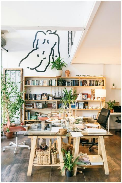 Bright, artistic office with bookshelves, plants,
