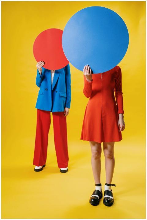 Two people in vibrant outfits holding large colore