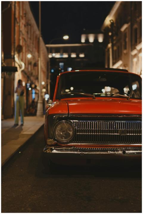 A classic red car parked on a dimly lit city stree