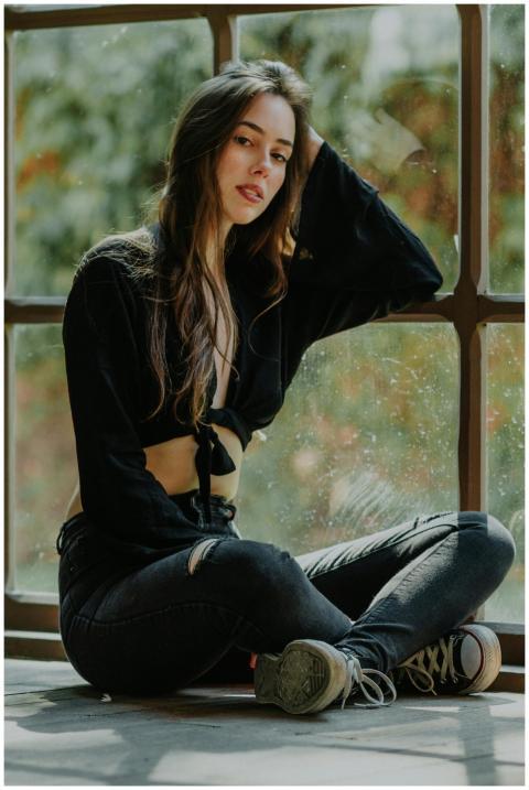 Fashionable young woman sitting by a window in cas