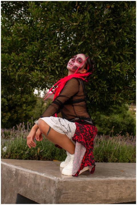 A person in vibrant makeup and costume striking a