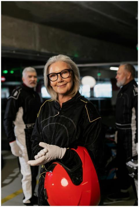 Elderly woman in racing suit and helmet, standing